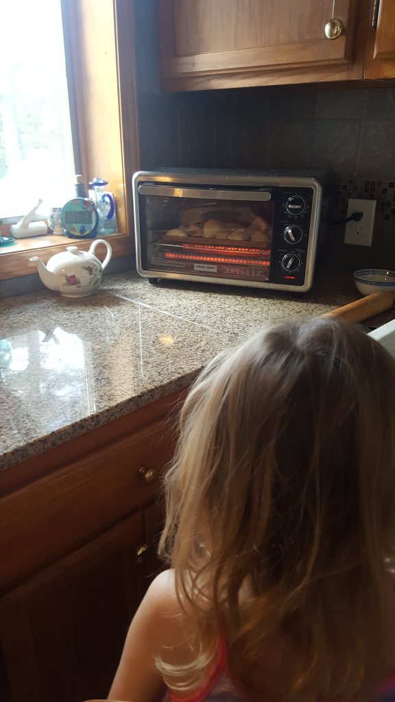 girl watching buns bake in the oven